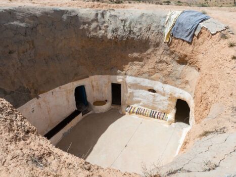 Sunken cave dwelling with whitewashed rooms in a dry landscape