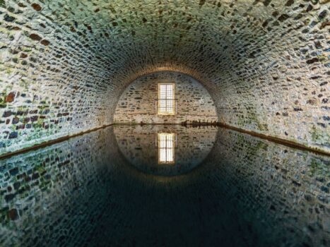 Stone-vaulted underground water chamber with a barred window and reflection